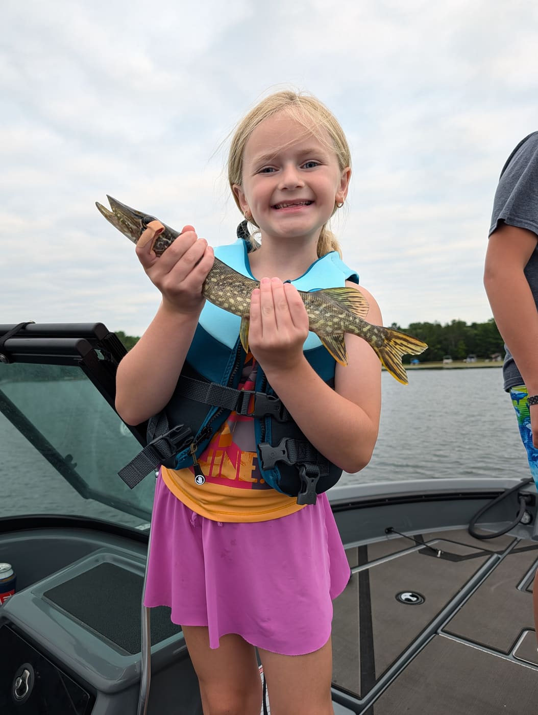 Young girl in a life jacket holding a pike