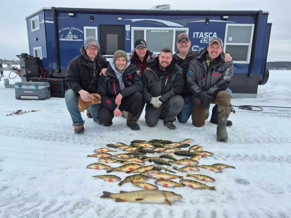 Ice fishing crew kneeling behind their catch on the ice