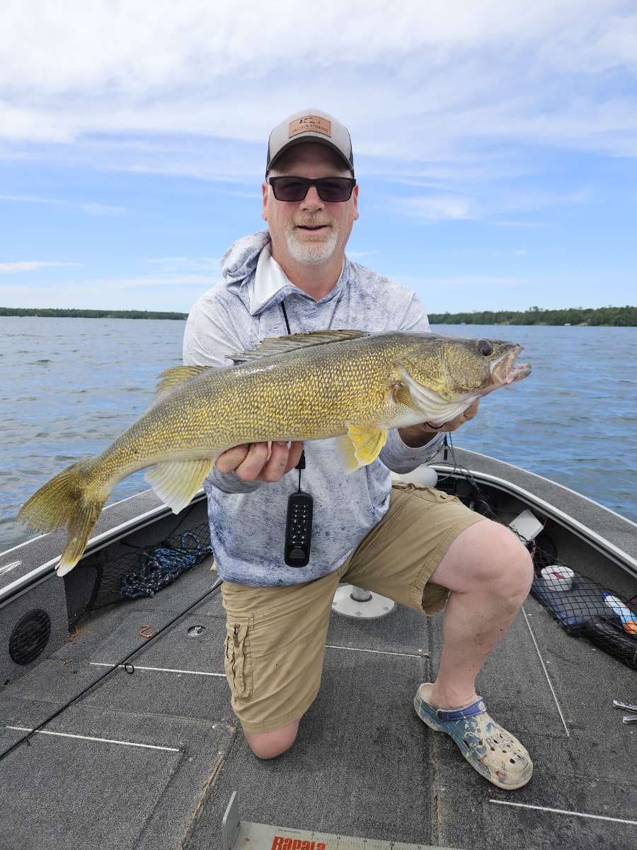 Angler in a Passive Fishing trucker hat with a trophy walleye